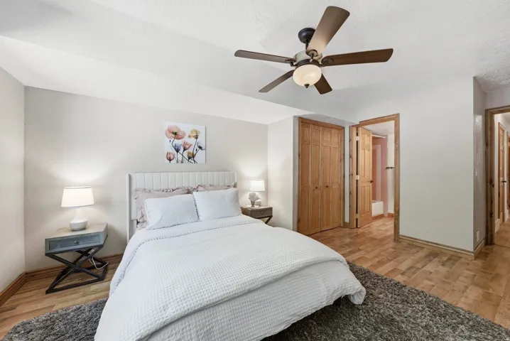 Bedroom featuring wood-finish flooring, a ceiling fan with integrated lighting, and light-toned walls