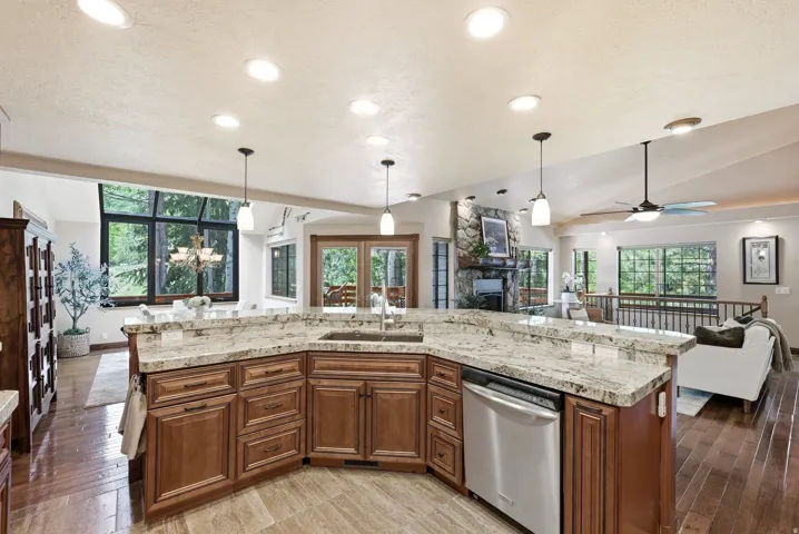 Kitchen island with granite countertops, integrated stainless steel dishwasher, and a double basin sink