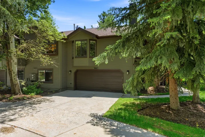 Two-story exterior with horizontal siding, an integrated garage, a bay window, and mature trees