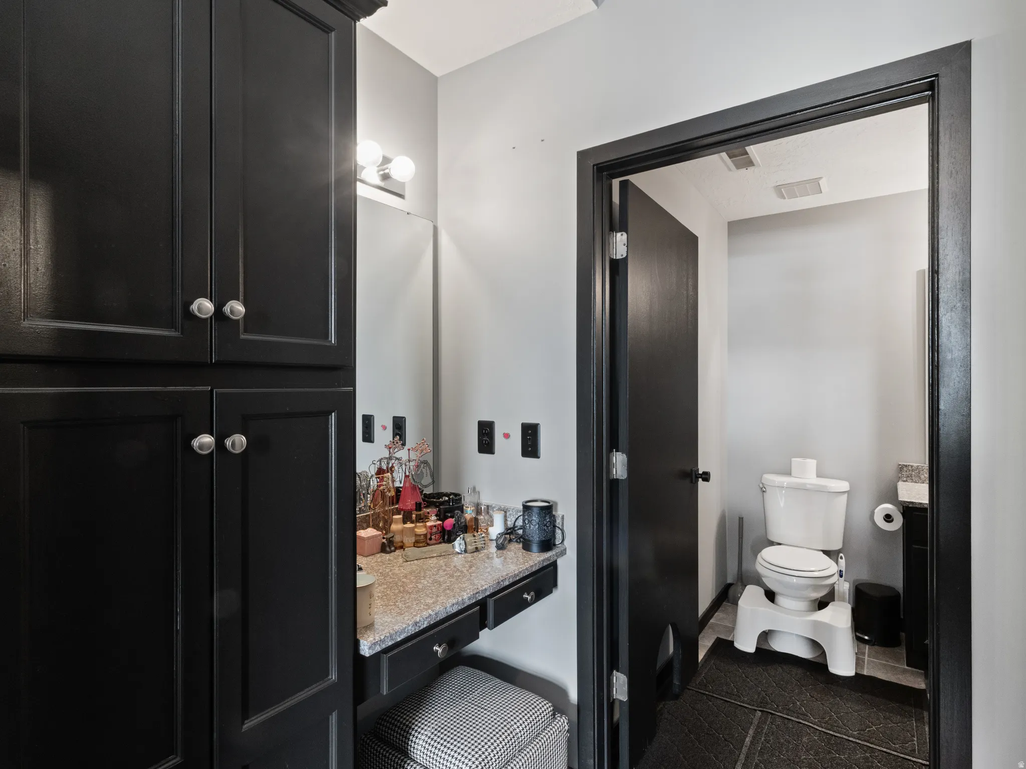 Bathroom vanity with black cabinetry, granite-finish countertop, and a wall-mounted vanity light fixture