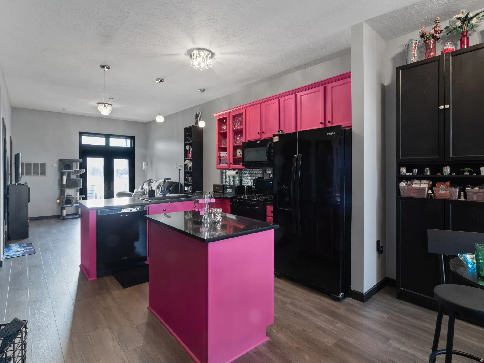 Kitchen featuring a central island, black appliances, and contrasting pink and black cabinetry