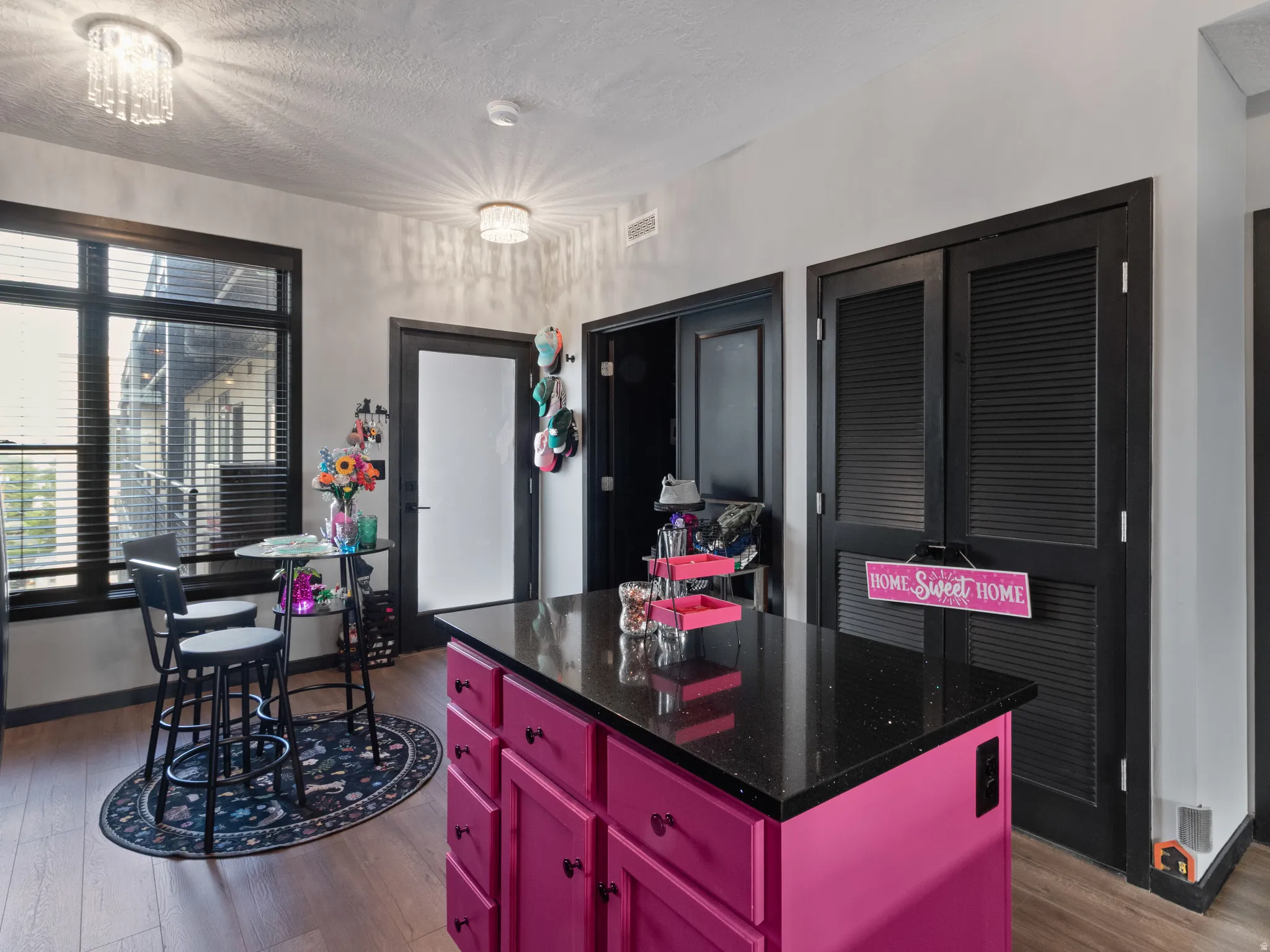 Kitchen island with a dark countertop and pink cabinetry
