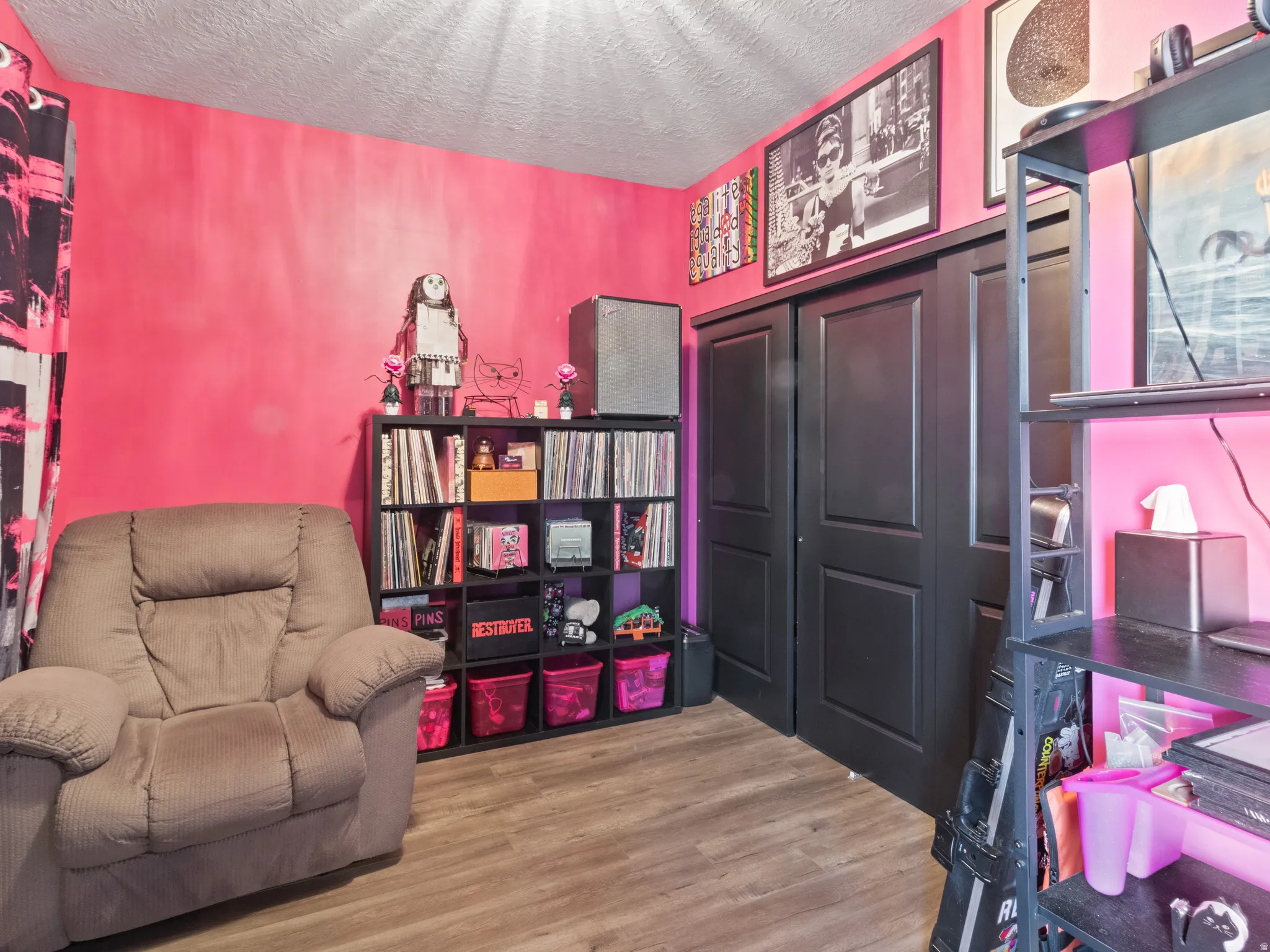 Room with wood-finish flooring, featuring a built-in closet with dark paneled bi-fold doors