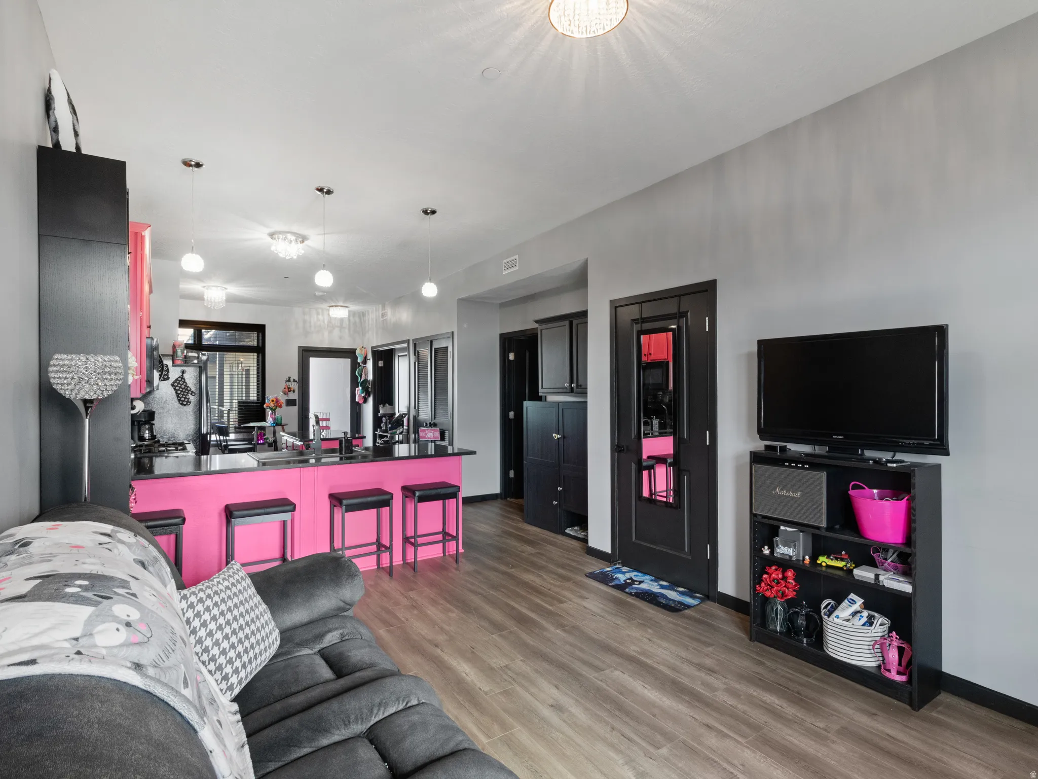 Open-concept living area featuring wood-finish flooring and a kitchen island with a black countertop