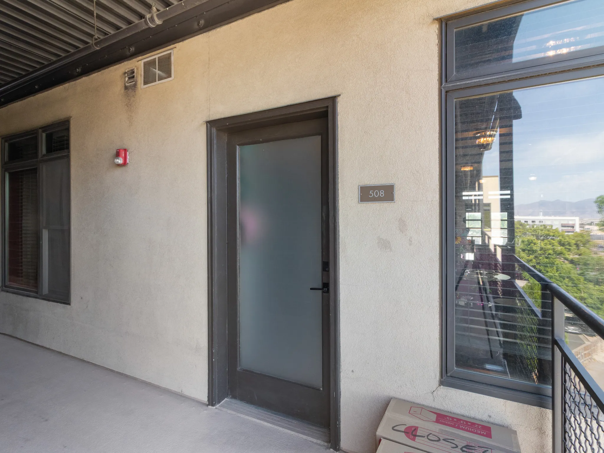 Entry door with frosted glass panel and dark frame, featuring a numerical address plate