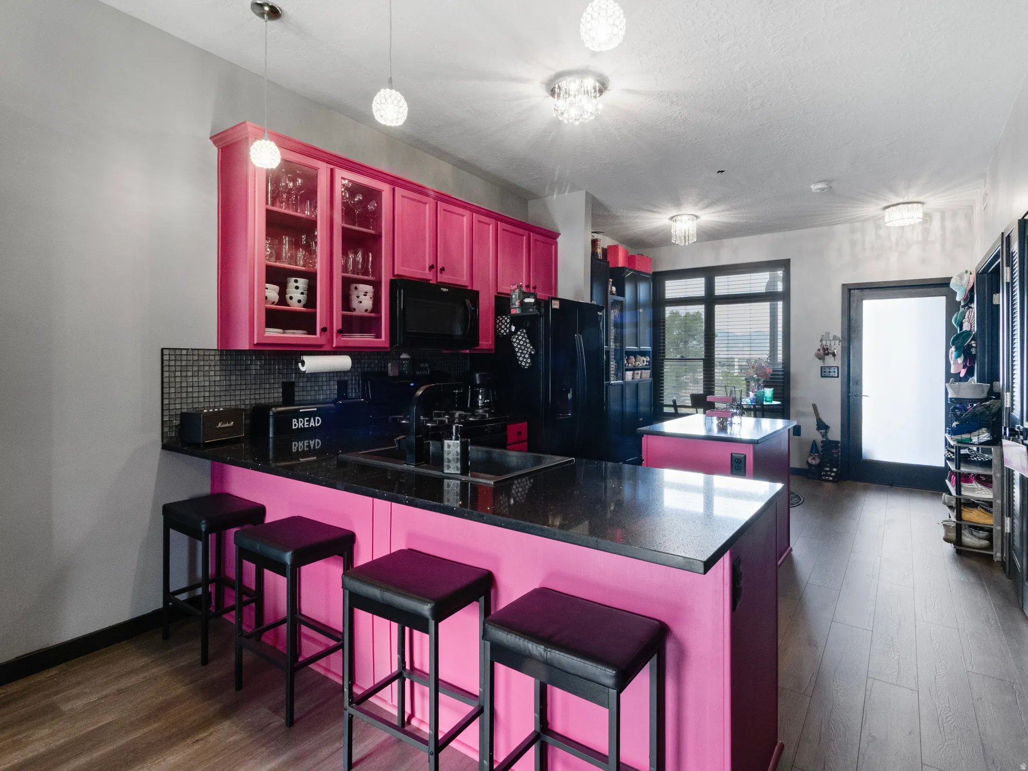 Open-concept kitchen featuring vibrant cabinetry, black countertops, and a tile backsplash