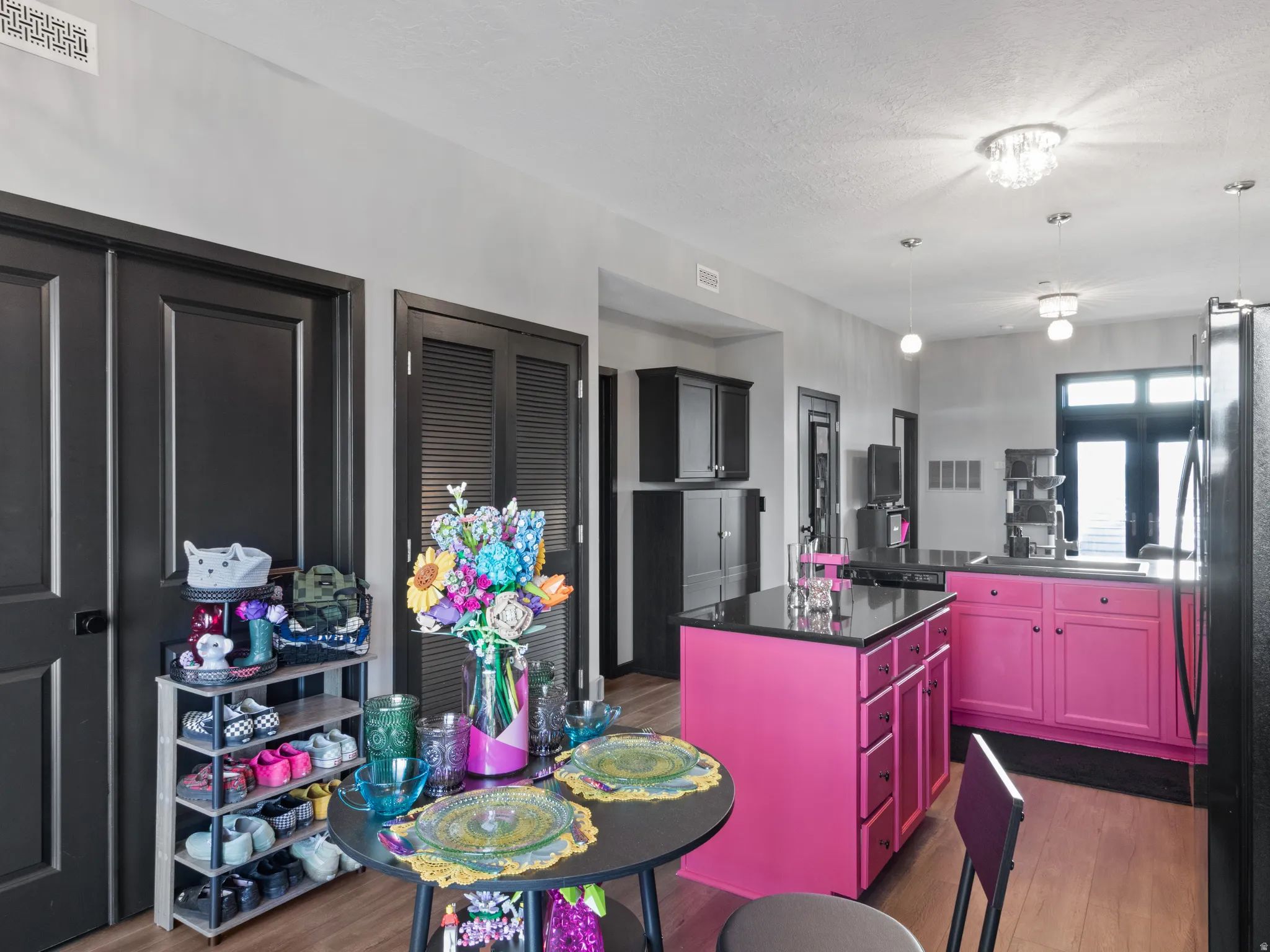 Open-concept kitchen featuring a vibrant island with integrated storage, black countertops, and wood-finish flooring