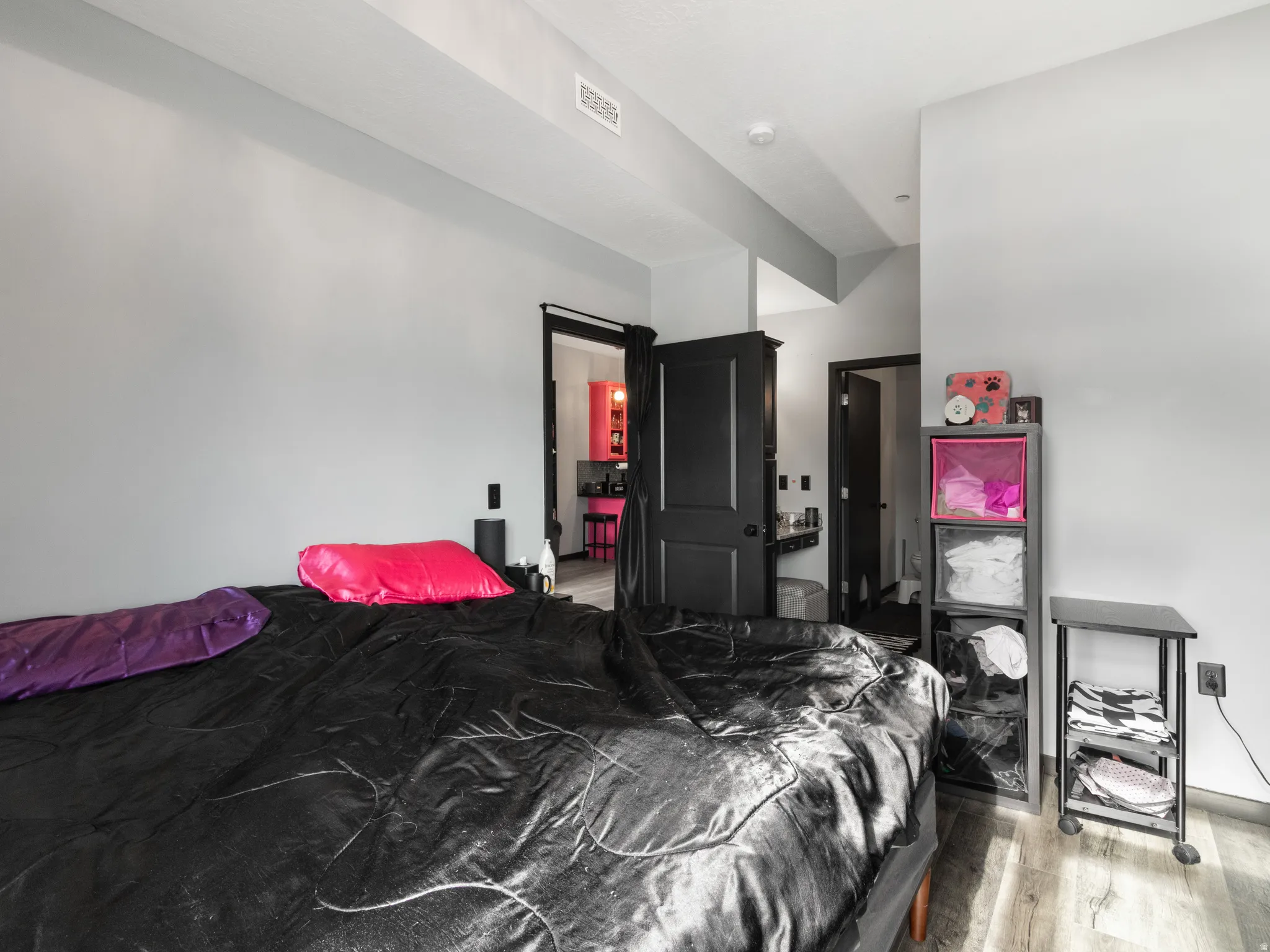Spacious room featuring light gray walls, wood-finish flooring, and black interior doors