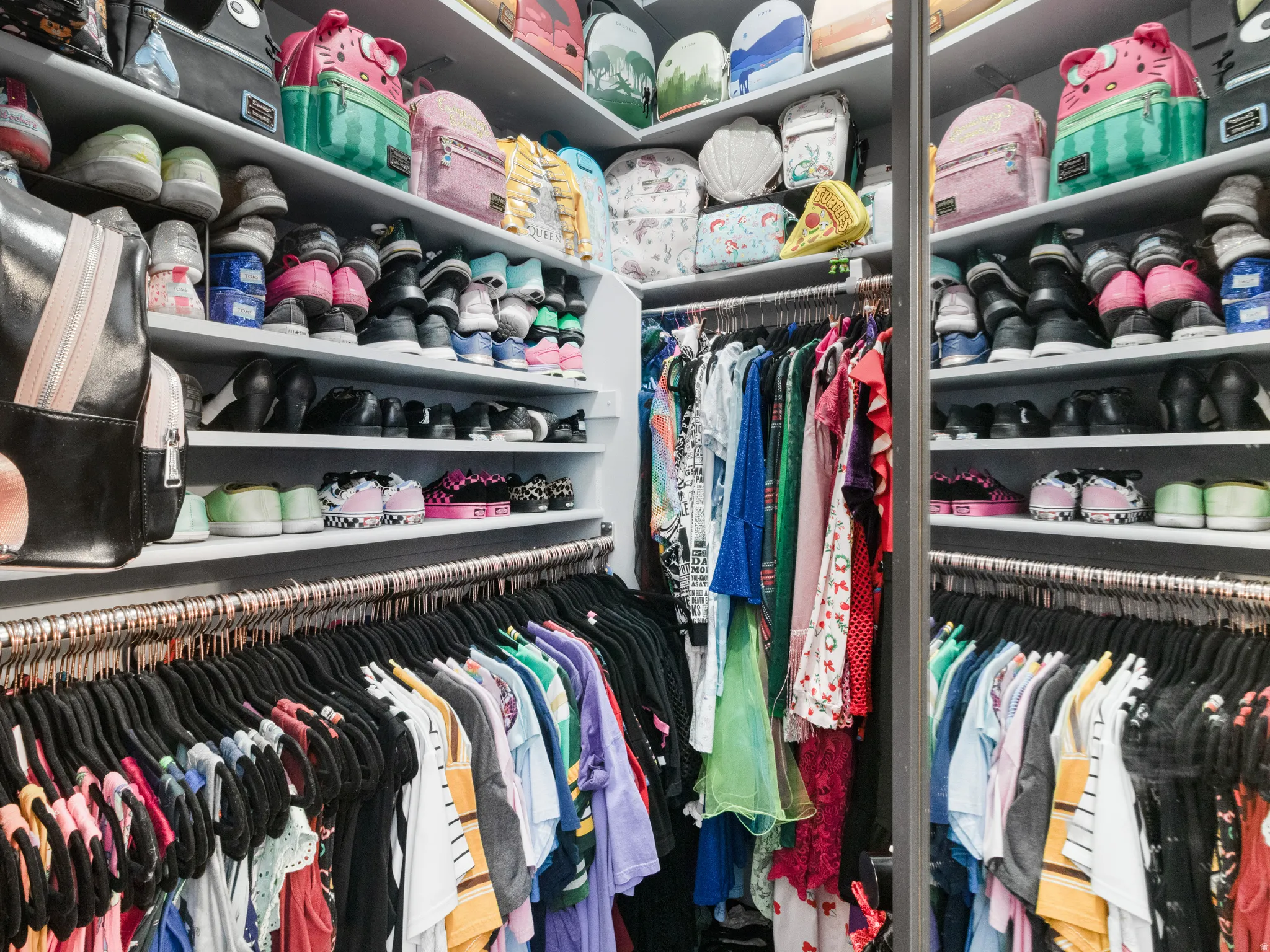 Built-in closet system featuring multiple shelving units, integrated hanging rods, and a reflective panel