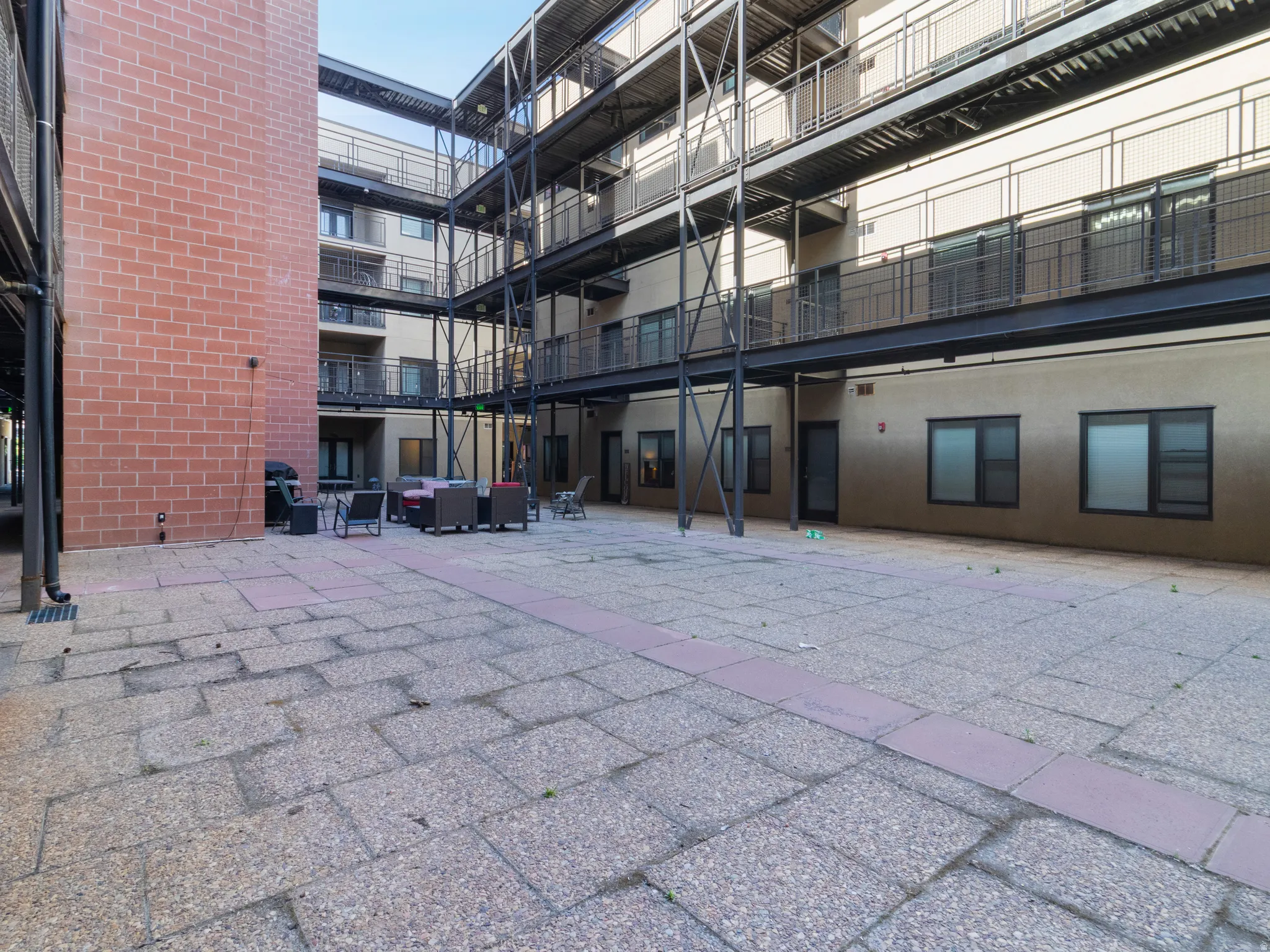 Courtyard patio with stone pavers, bordered by a brick facade and multi-level balconies with metal railings