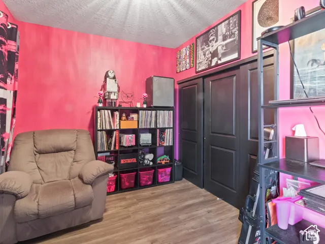 Room with wood-finish flooring, featuring a built-in closet with dark paneled bi-fold doors