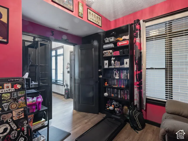 Room featuring wood-finish flooring, a built-in shelving unit, and a window with blinds