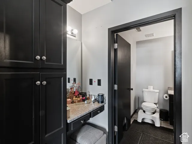 Bathroom vanity with black cabinetry, granite-finish countertop, and a wall-mounted vanity light fixture