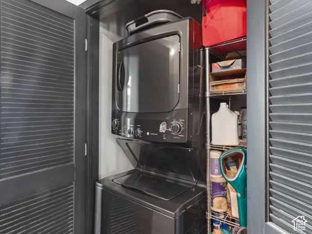 Stackable washer and dryer unit with dark finish, situated within a louvered bi-fold door enclosure