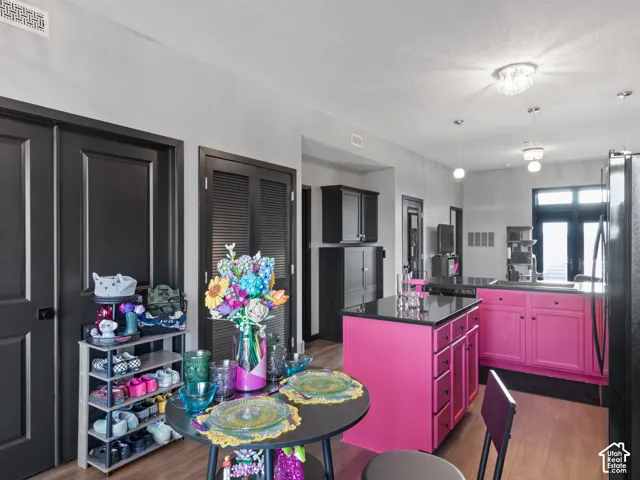 Open-concept kitchen featuring a vibrant island with integrated storage, black countertops, and wood-finish flooring