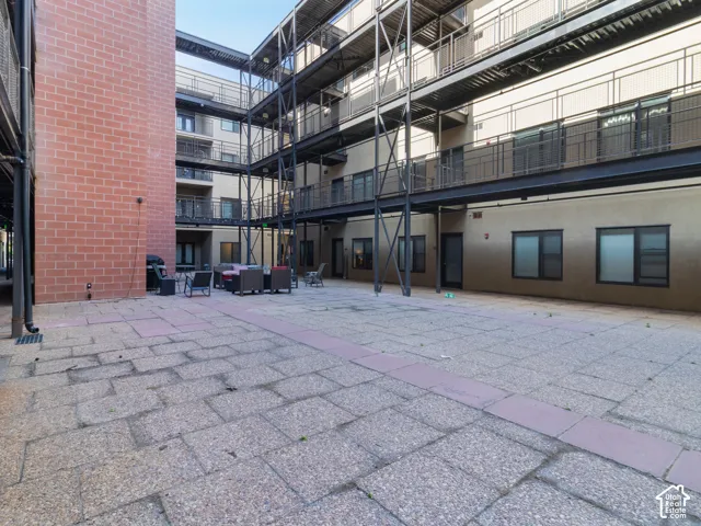 Courtyard patio with stone pavers, bordered by a brick facade and multi-level balconies with metal railings