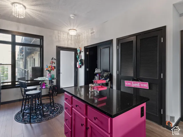 Kitchen island with a dark countertop and pink cabinetry