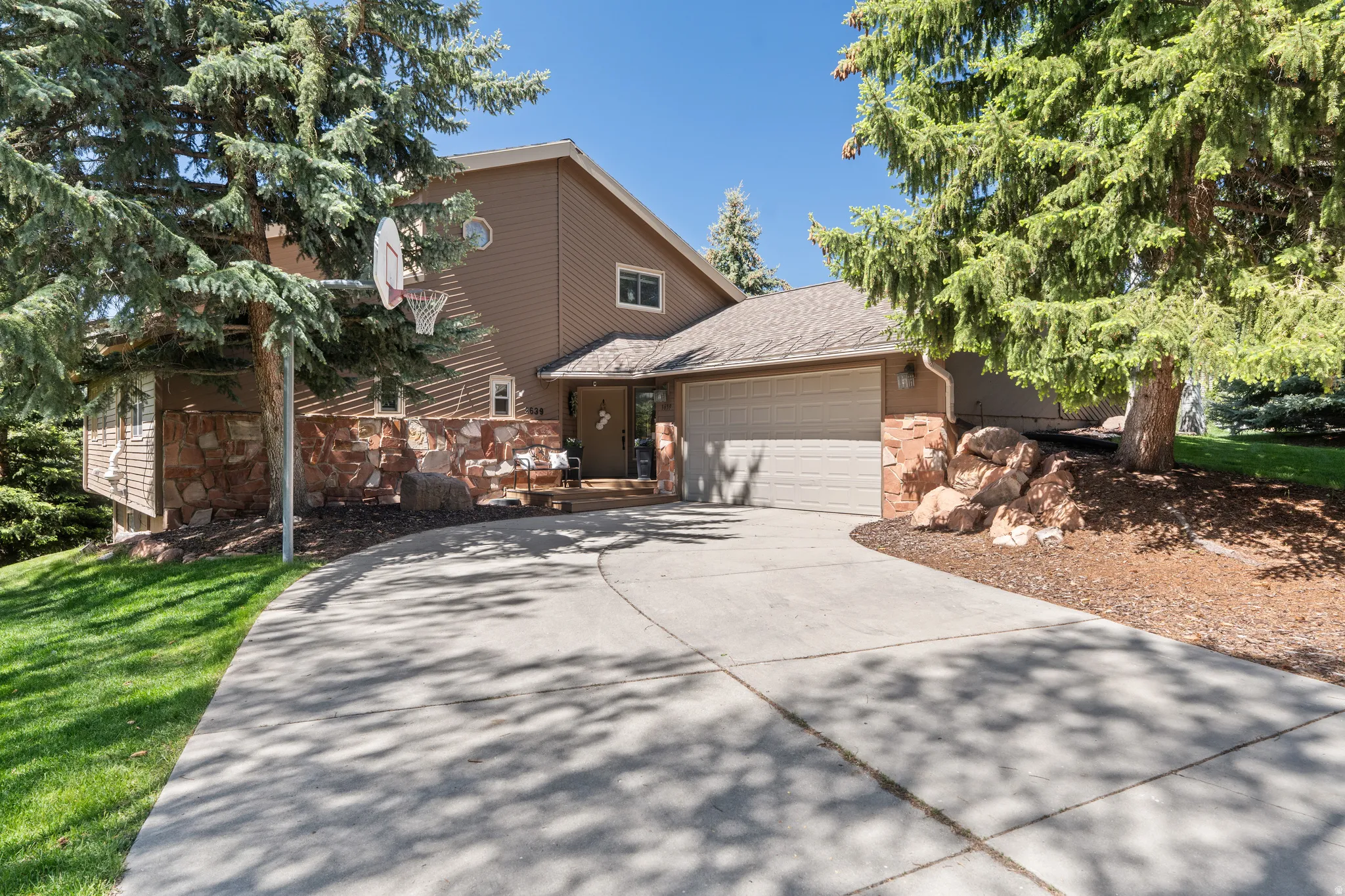 Exterior featuring a two-car garage, stone accents, and a sloped concrete driveway