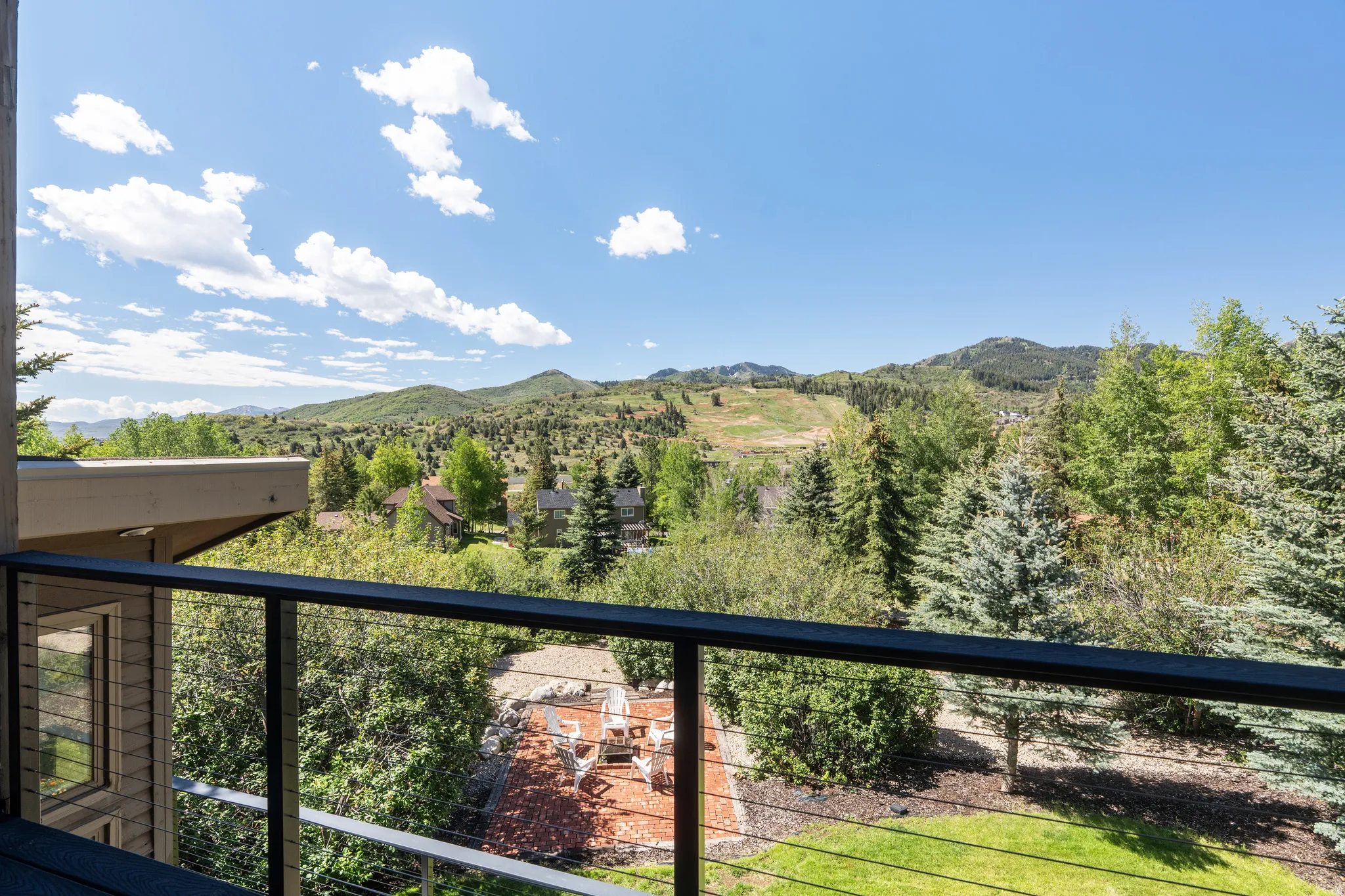 Cable railing balcony overlooking a mountain landscape with abundant trees and residential structures