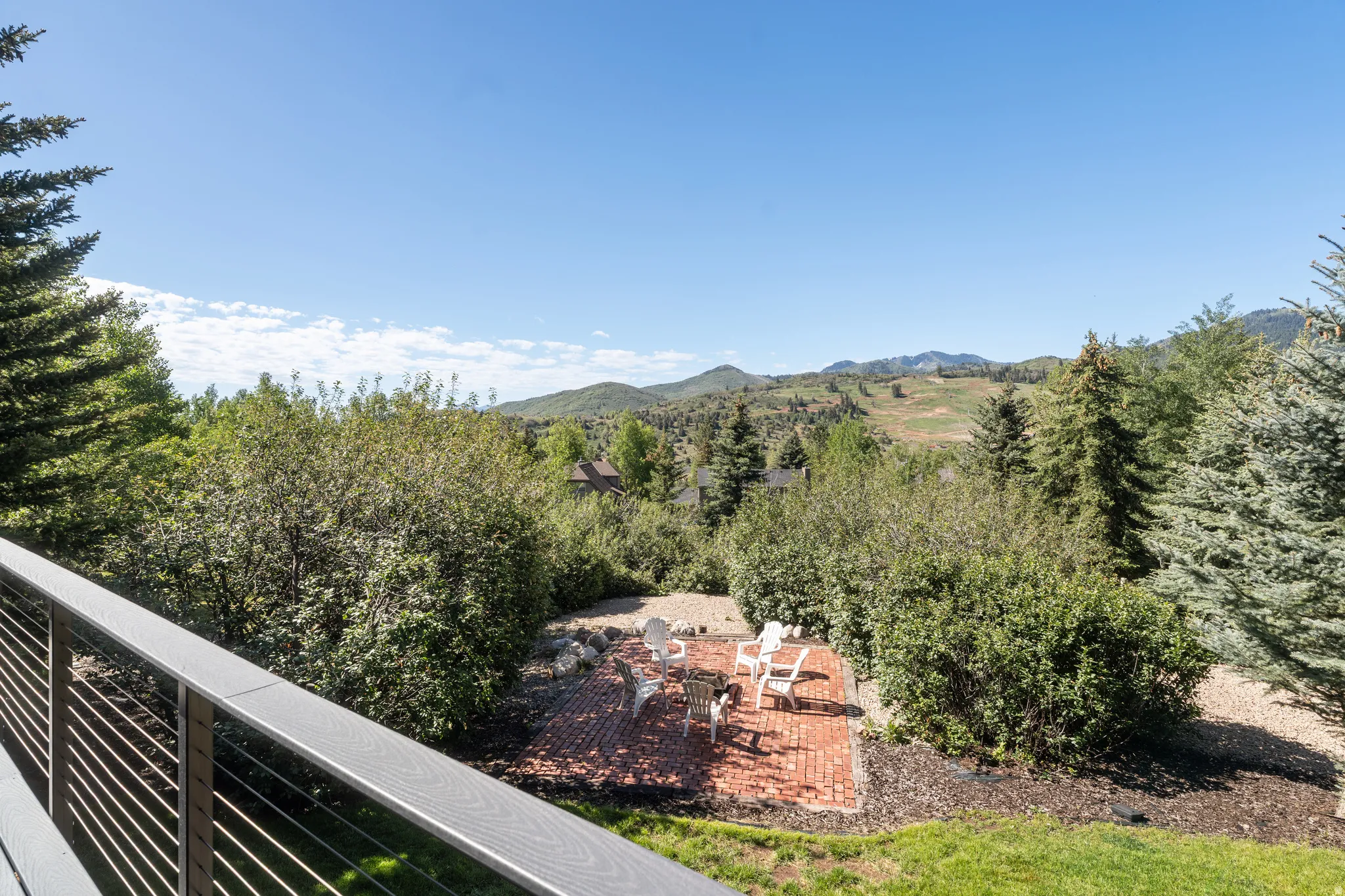 Outdoor living space featuring a brick patio and a surrounding landscape of mature trees