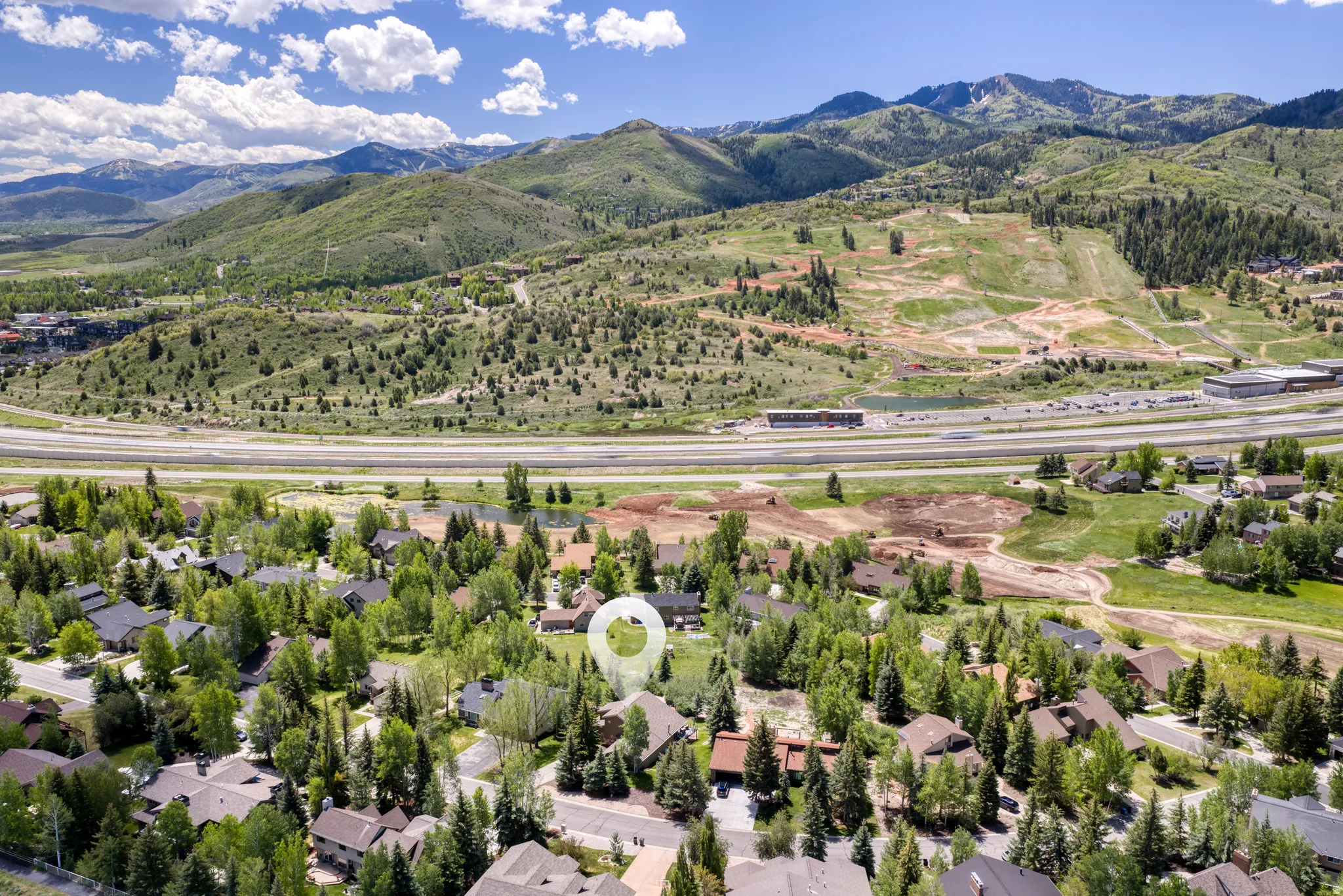 Aerial landscape featuring a residential community amidst lush greenery and mountainous terrain