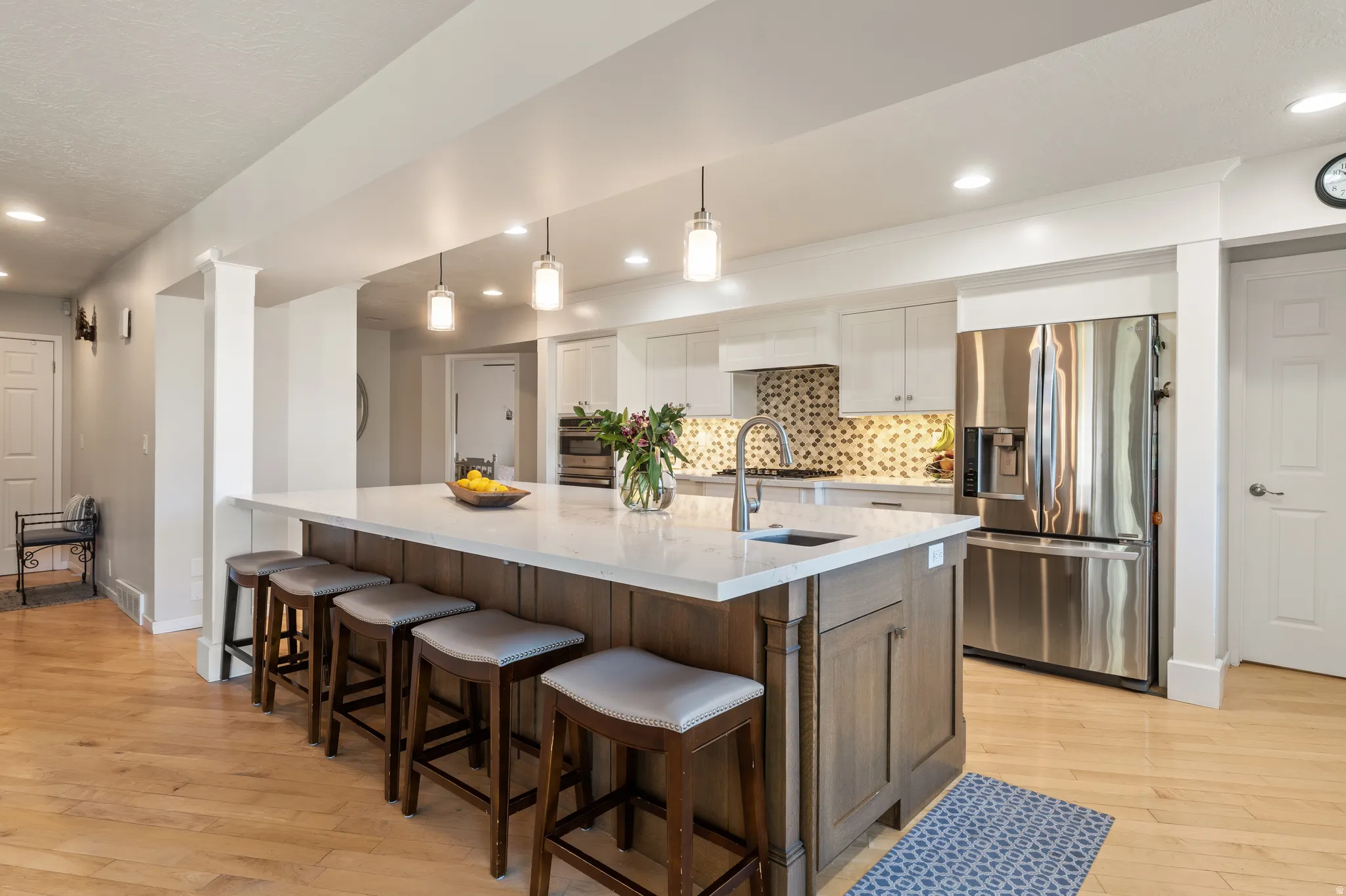 Gourmet kitchen featuring a large island with seating, stone countertops, stainless steel appliances, and a mosaic tile backsplash