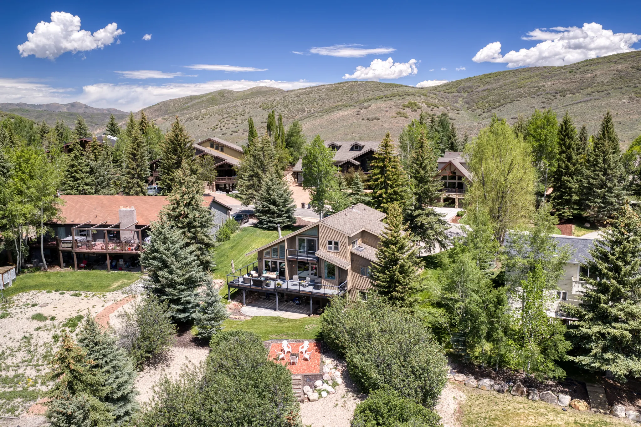 Contemporary multi-level residence featuring multiple decks, mature trees, and an outdoor fire pit area