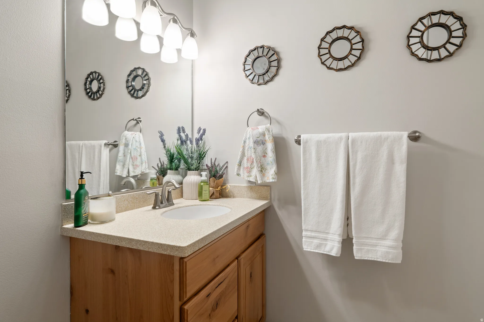 Bathroom vanity featuring a light-toned countertop, undermount sink, and wood-finish cabinetry