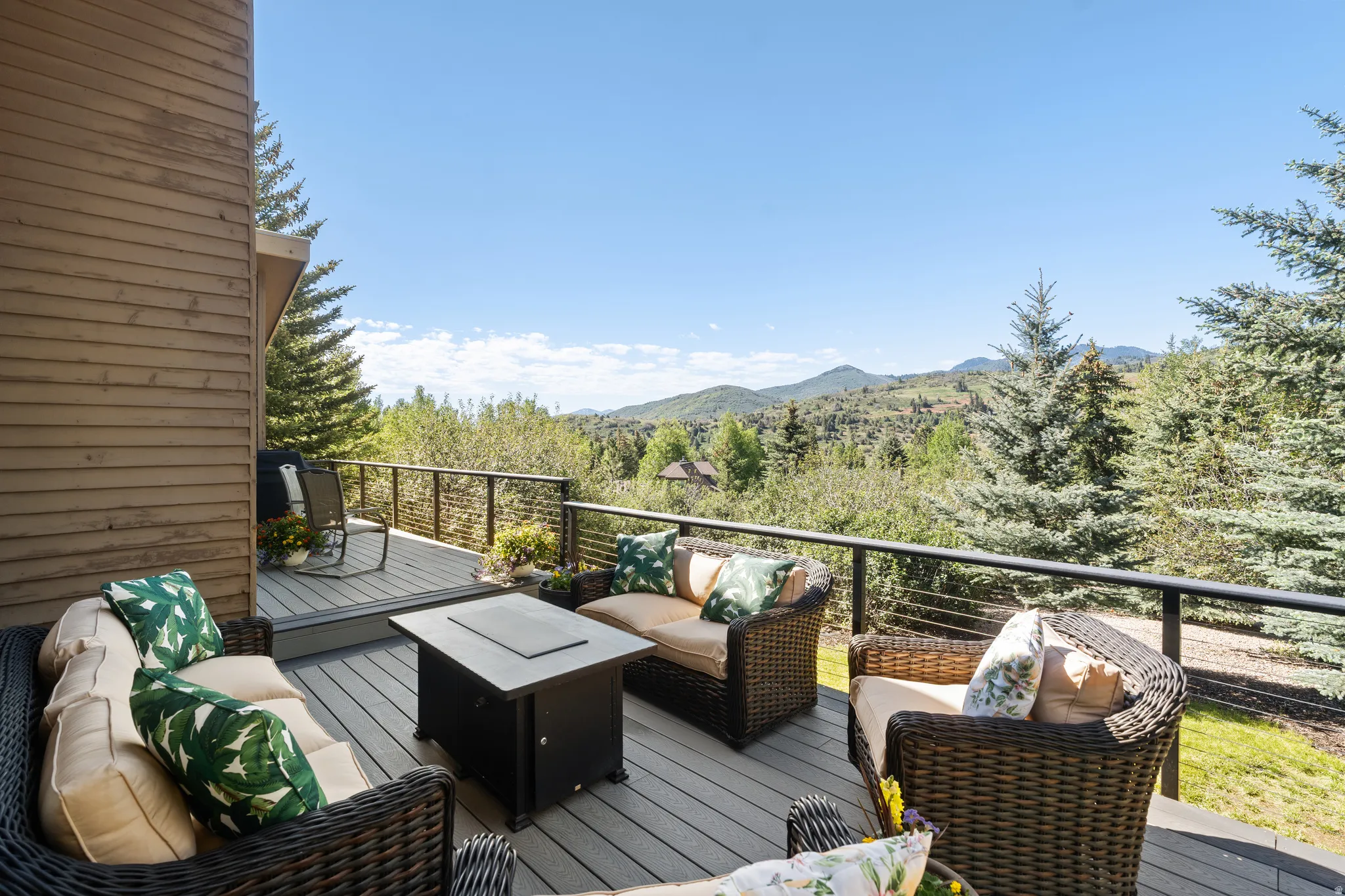 Spacious outdoor deck featuring composite decking, dark railings, and a mountainous backdrop