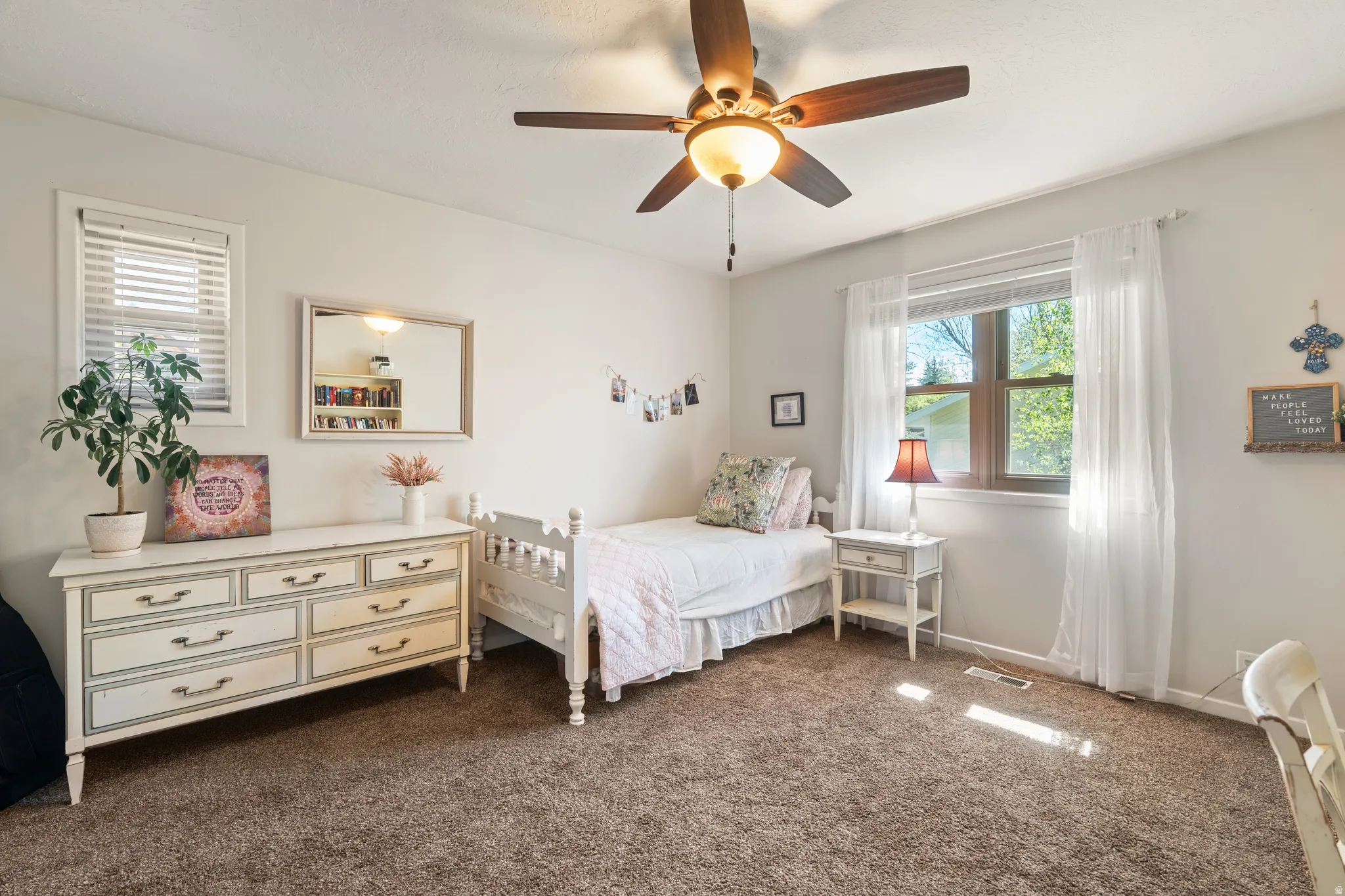 Neutral wall paint with textured carpet flooring, complemented by two windows with white blinds and sheer curtains