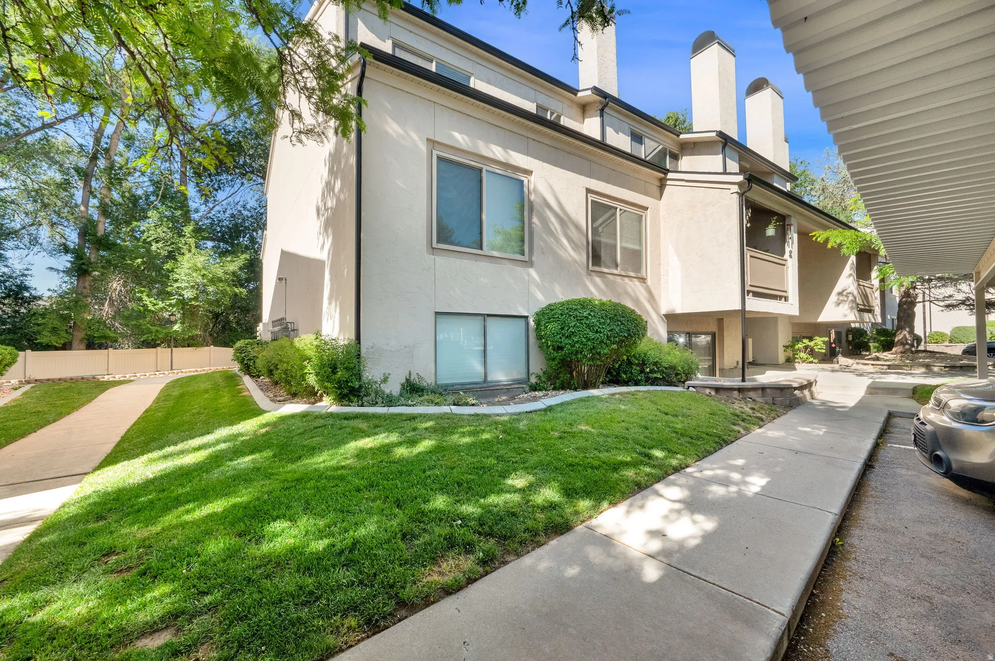Contemporary multi-level exterior with stucco finish, prominent chimneys, and mature landscaping