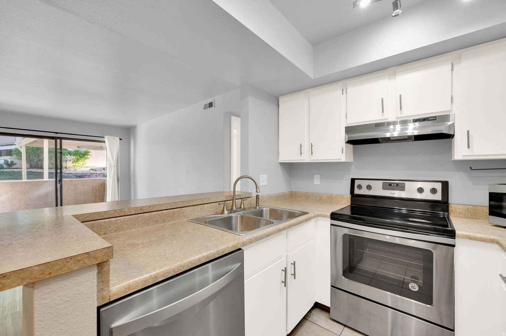 Kitchen featuring white cabinetry, stainless steel appliances including a range and dishwasher, and a double basin sink