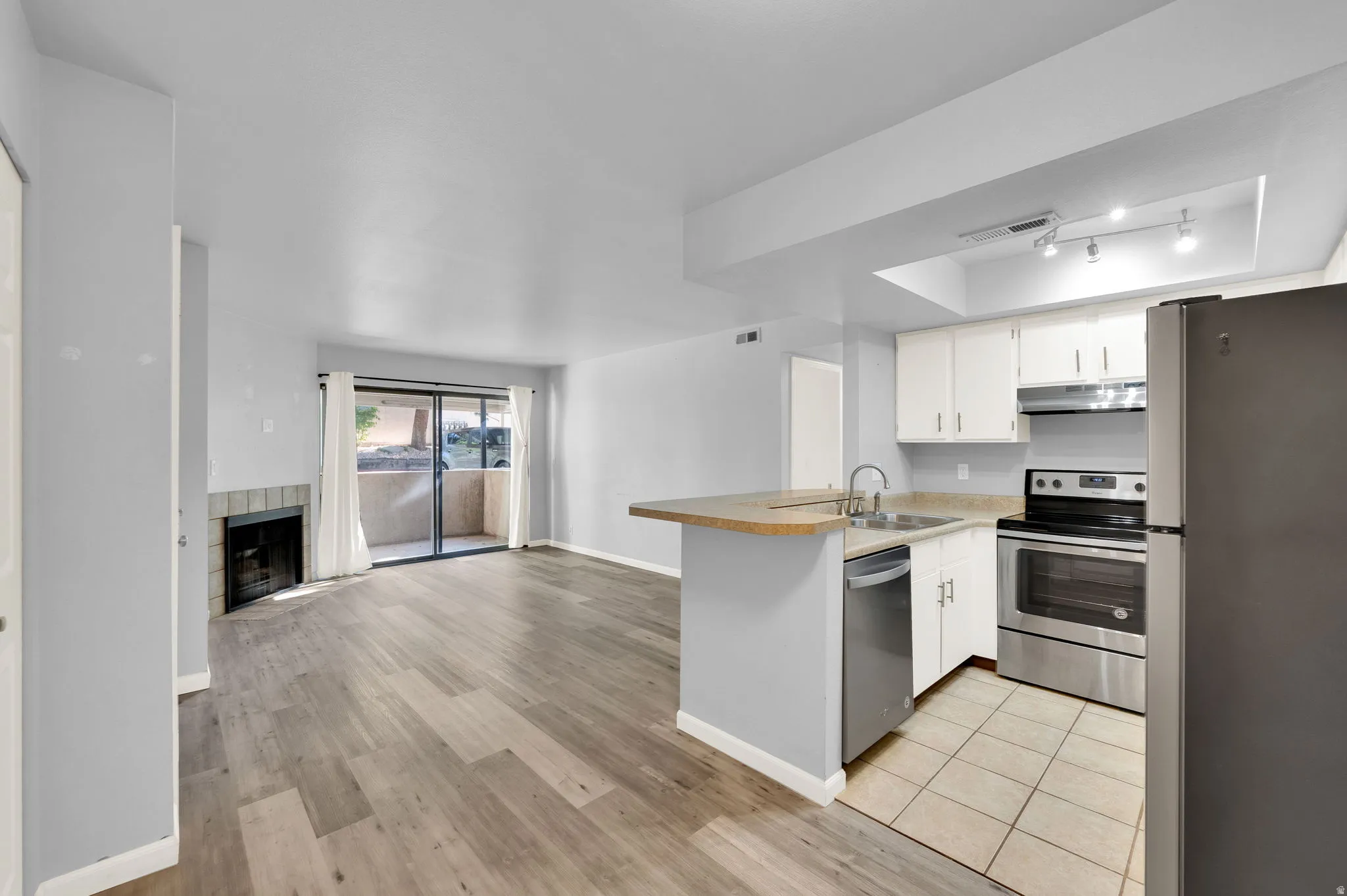 Open-concept living area featuring wood-finish flooring, a fireplace with a tiled surround, and sliding glass doors to the outdoor space