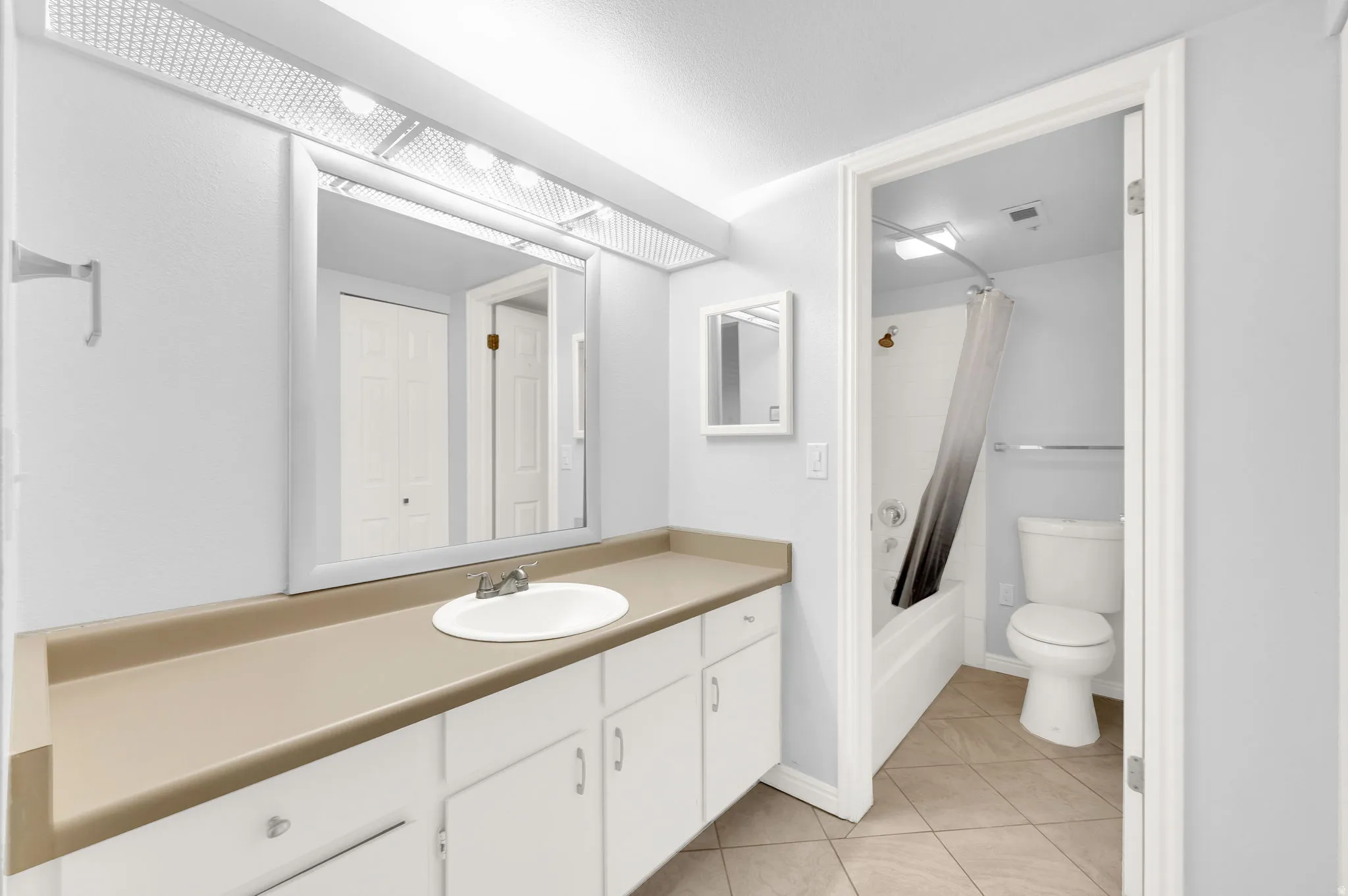 Bathroom vanity featuring a single basin sink, laminate countertop, and white cabinetry