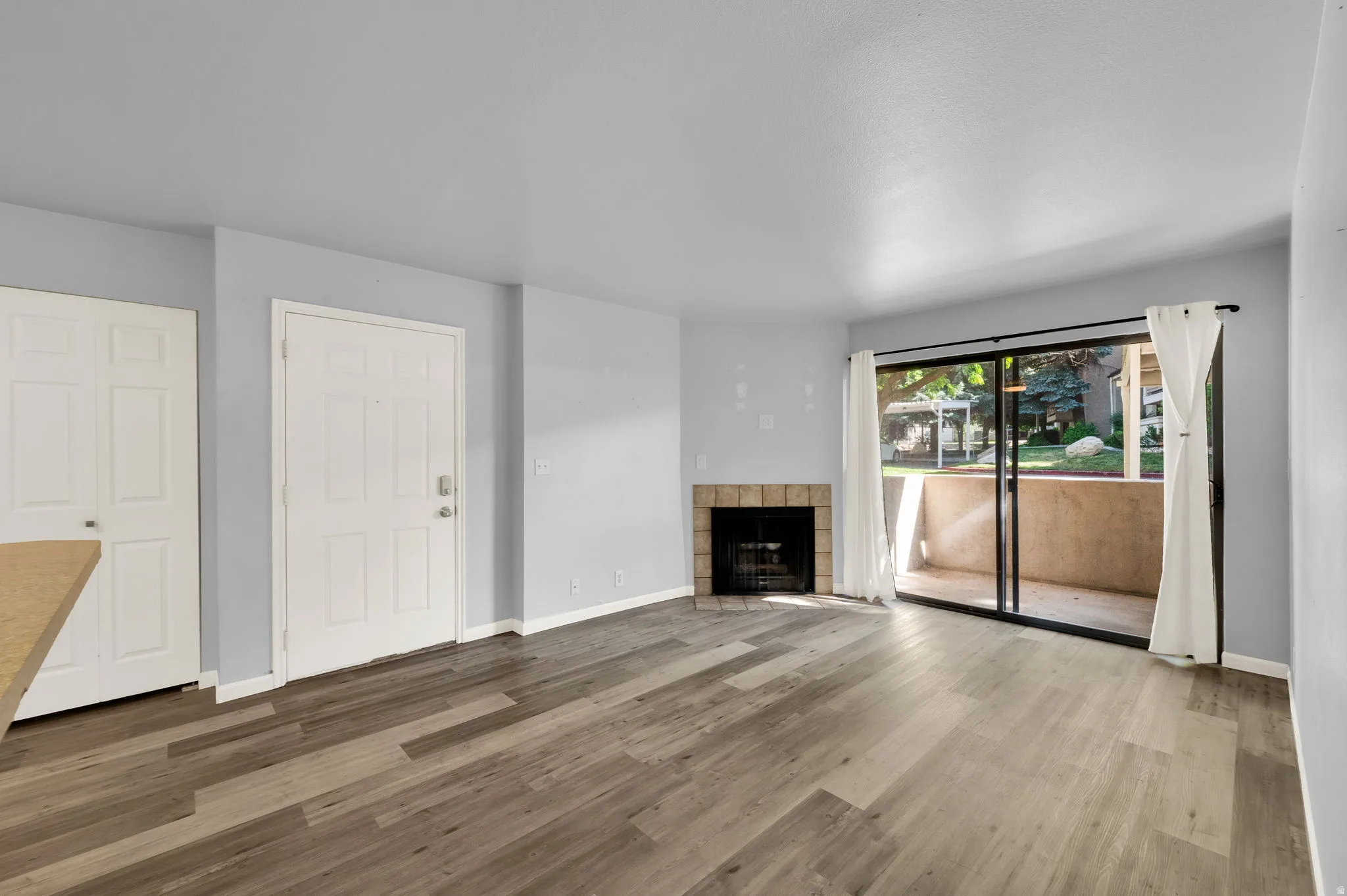 Living area featuring wood-finish flooring, a stone-surround fireplace, and light gray wall paint