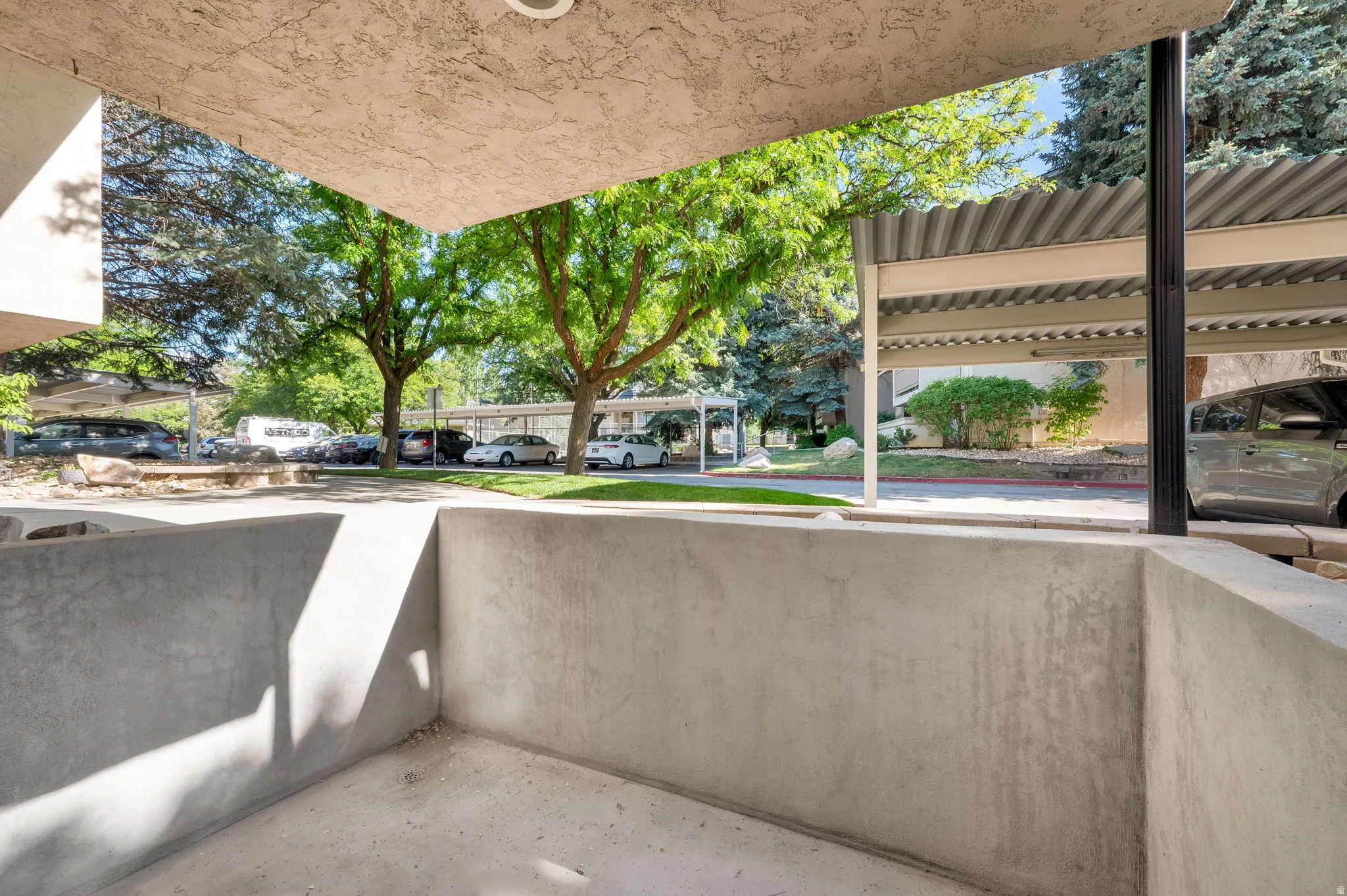Concrete patio area with a textured stucco ceiling and recessed lighting, offering a private outdoor space