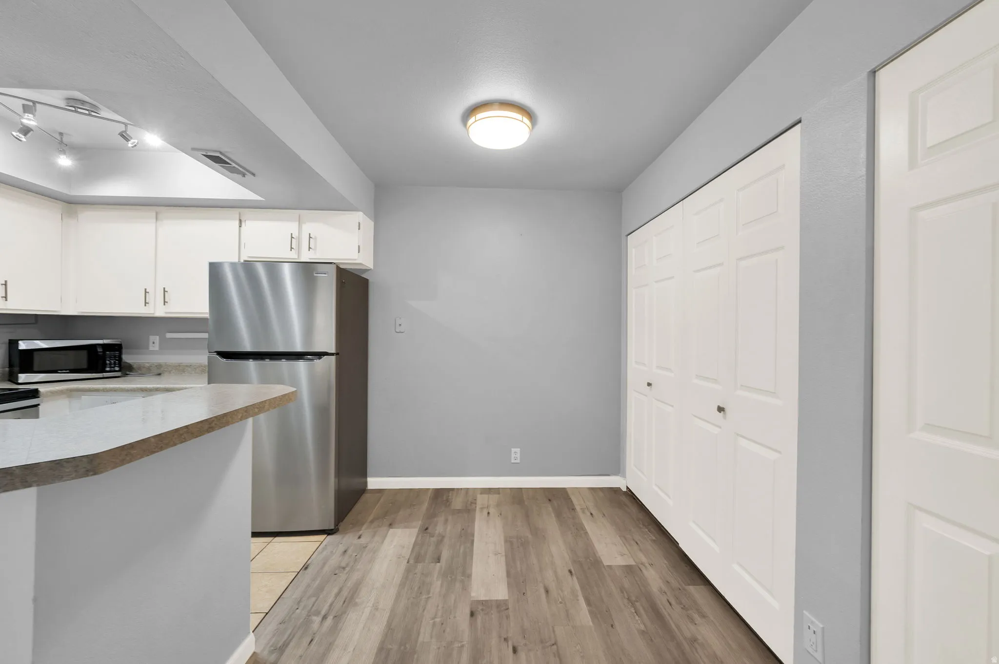 Kitchen featuring white cabinetry, stainless steel appliances, and a breakfast bar with a solid surface countertop
