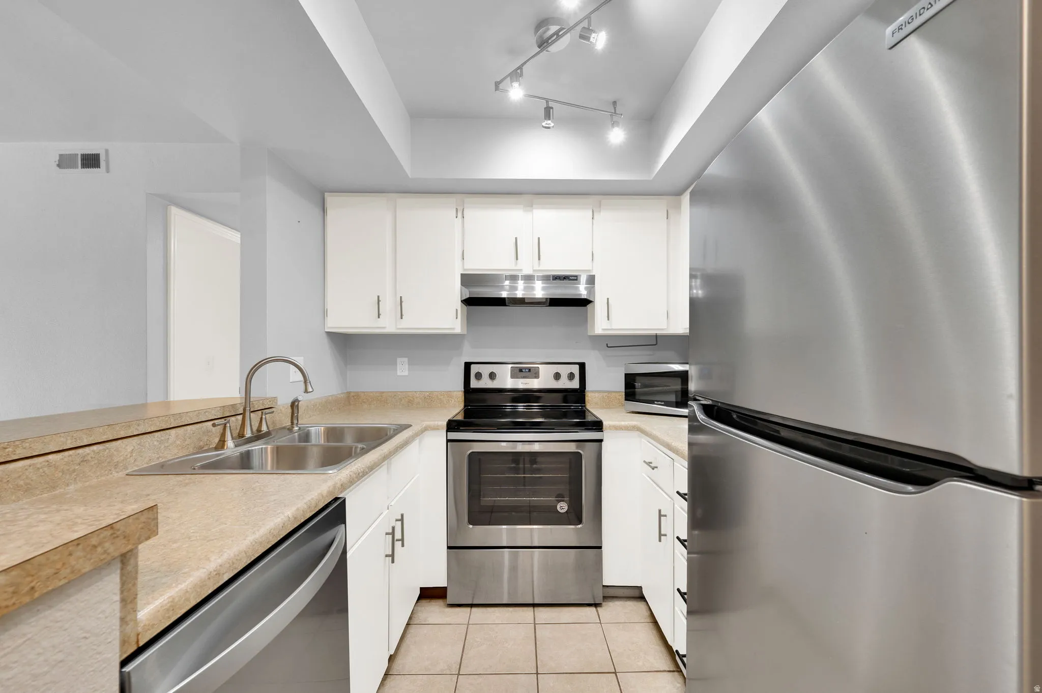 U-shaped kitchen featuring a stainless steel refrigerator, range, and dishwasher