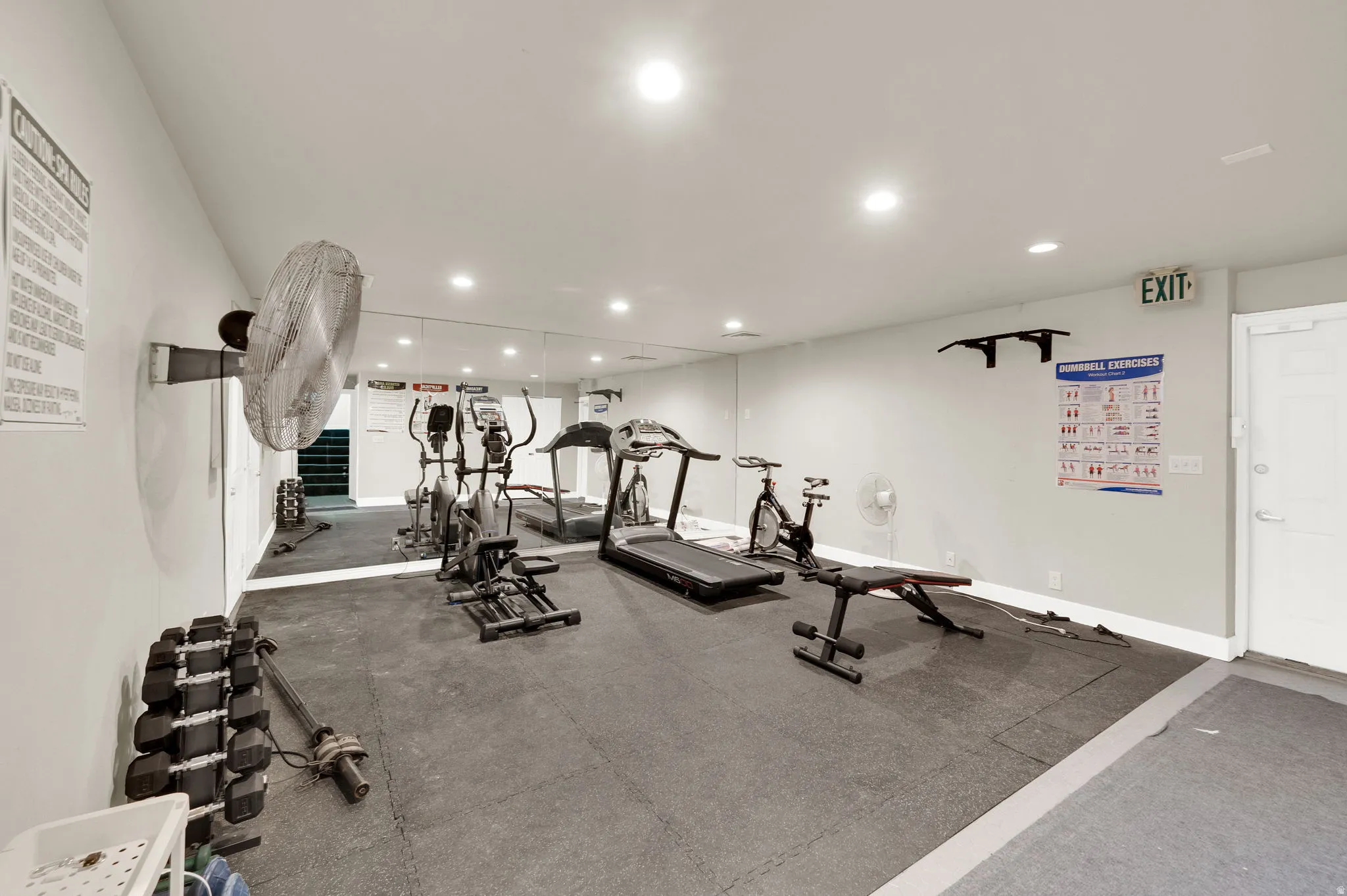 Dedicated fitness space featuring mirrored walls, recessed lighting, and resilient mat flooring