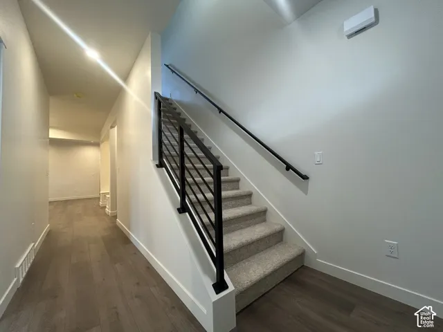 Staircase featuring a matte black metal railing with horizontal balusters, carpeted treads, and wood-finish flooring
