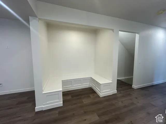 Built-in white recessed bench featuring wainscoting panel detail and wood-finish flooring