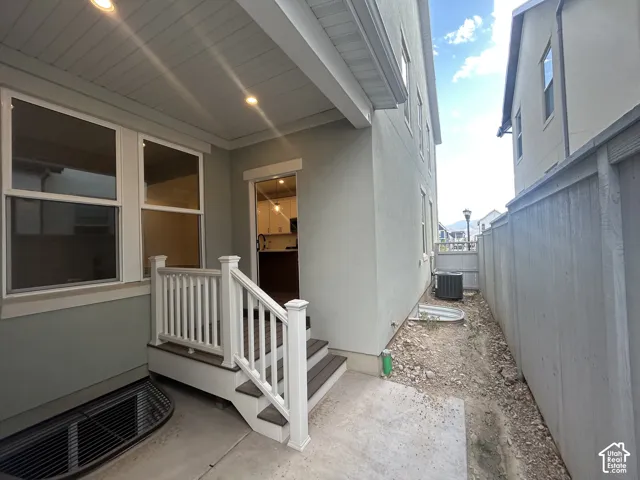 Covered patio featuring a composite deck with white railings, stucco exterior, recessed lighting, and a fenced side yard area
