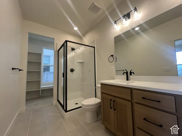 Bathroom featuring a vanity with a light wood-finish cabinet and solid surface countertop, glass-enclosed shower with black metal framing, matte black plumbing fixtures, oversized frameless mirror, and built-in shelving