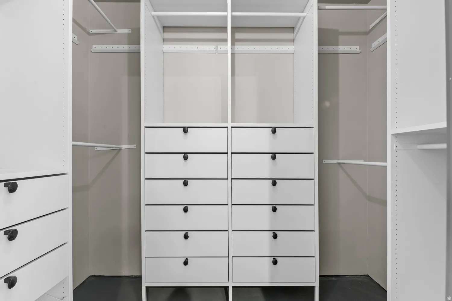 Custom closet system featuring multiple integrated drawer units with matte black hardware, adjustable shelving, and hanging rods