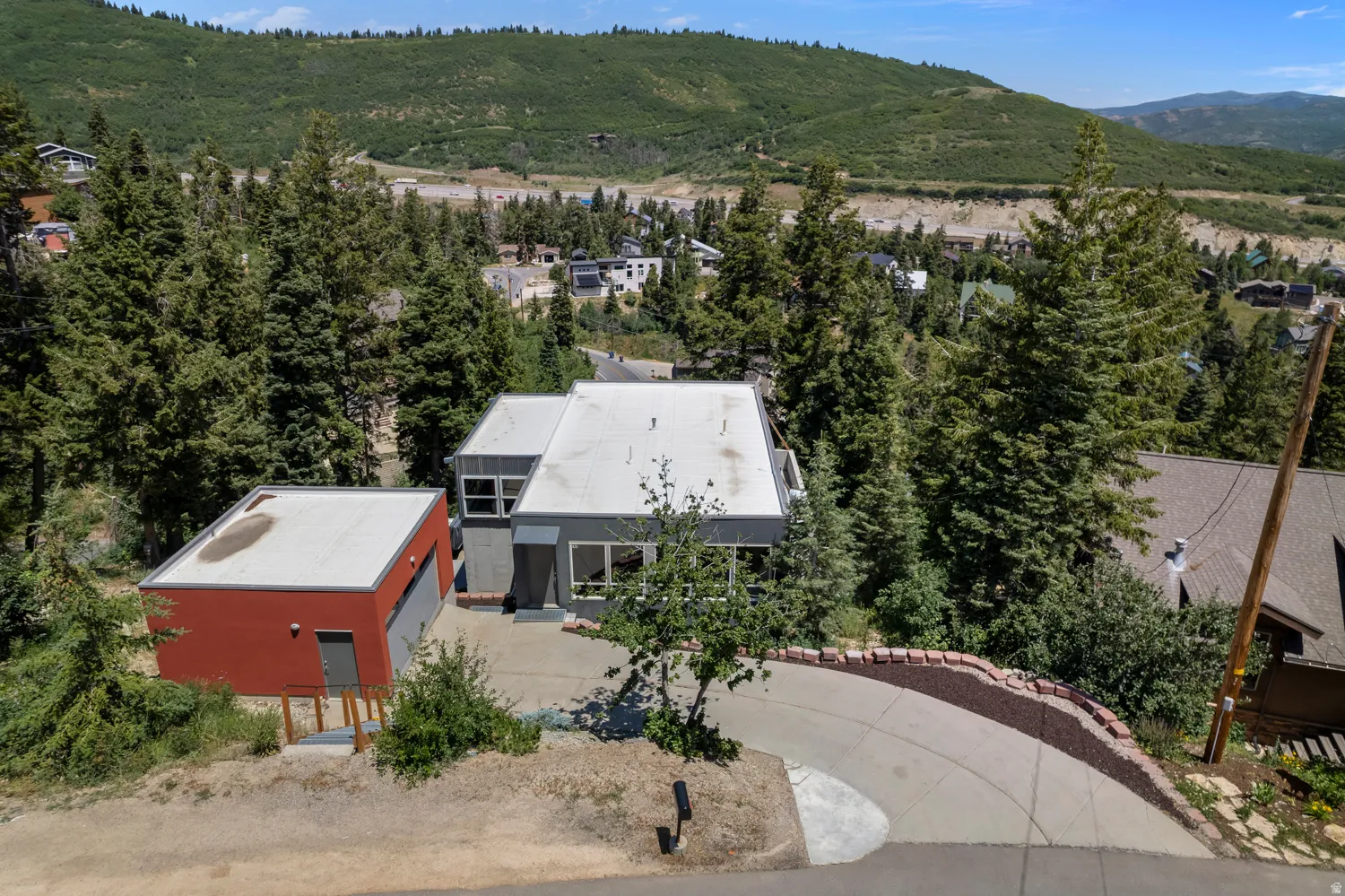Modern architecture with a flat roofline, featuring a gray facade and a contrasting red outbuilding