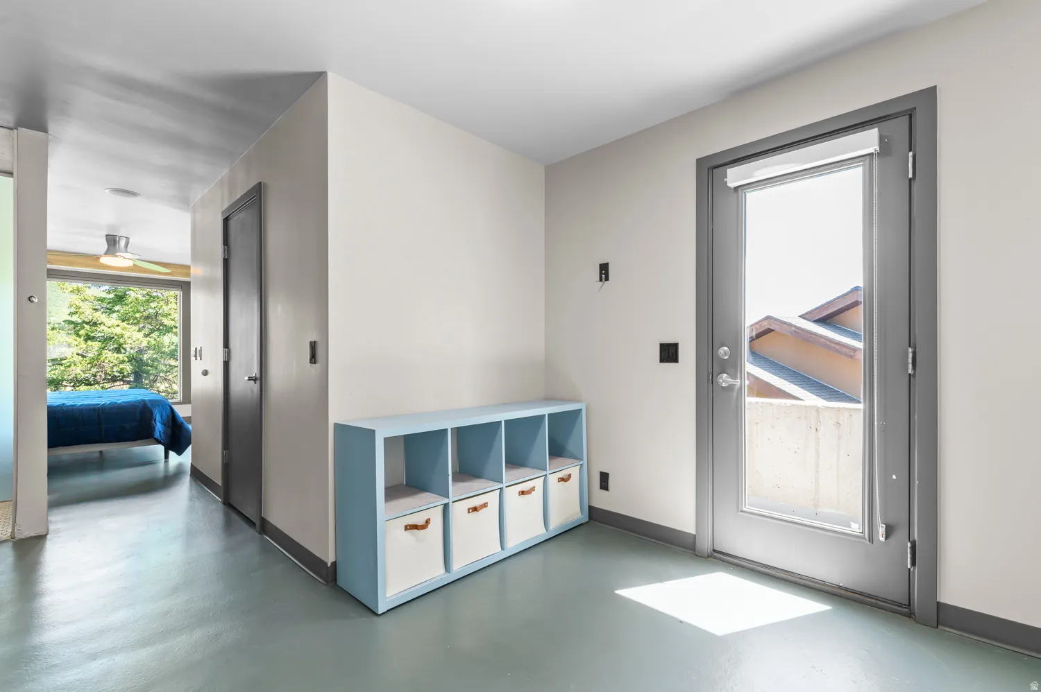 Light-filled interior space with a full-light exterior door, neutral wall tones, and gray trim