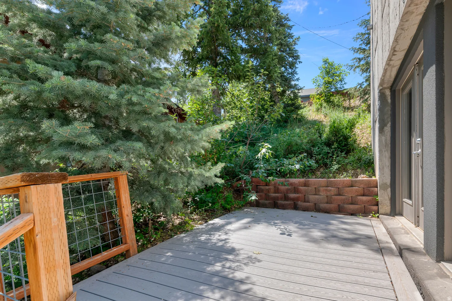 Outdoor deck featuring composite decking, wood railing with wire mesh infill, and direct access to the interior via a glass-paneled door