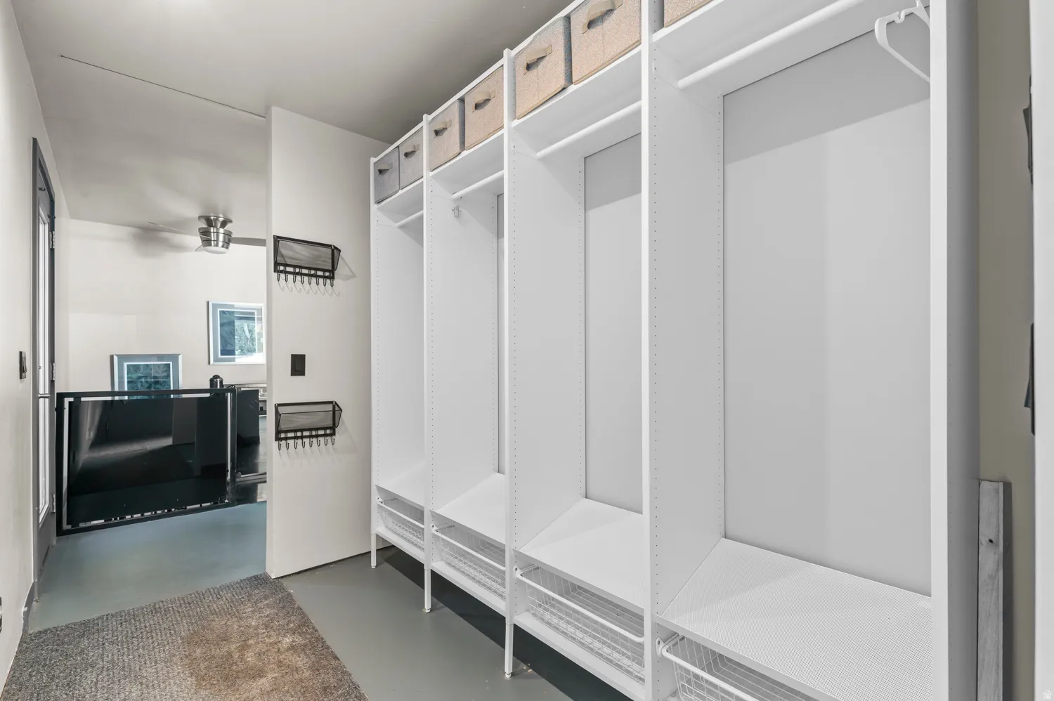 Built-in white storage system featuring multiple compartments, hanging rods, and wire basket drawers