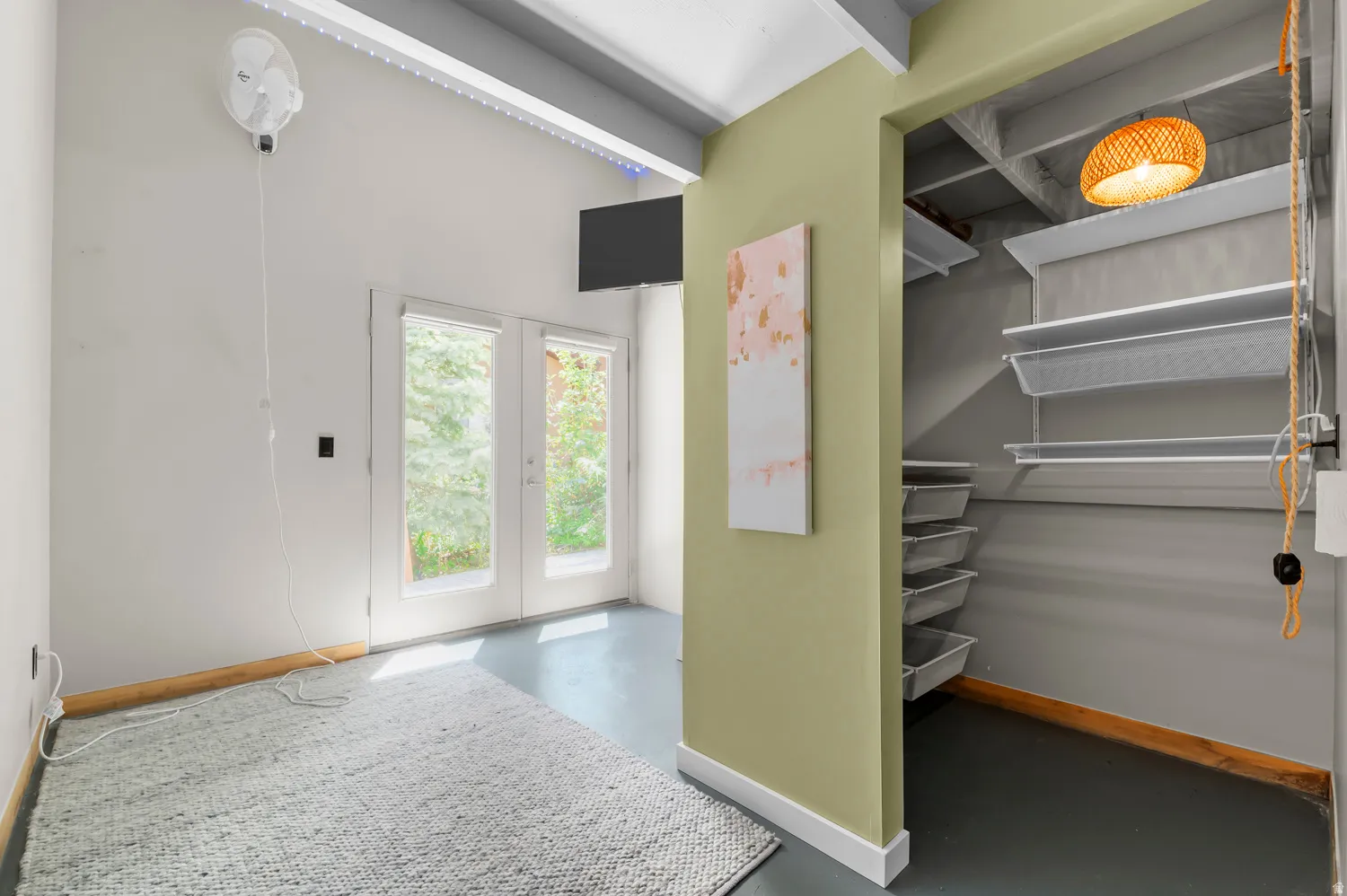 Room featuring light gray walls, exposed ceiling beams, and concrete flooring