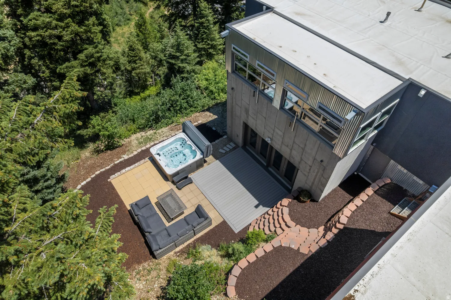Modern exterior featuring a composite deck, an integrated hot tub, and a stone paver patio